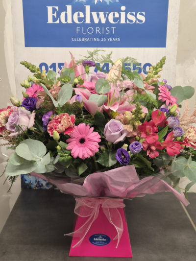 Out of This World - A beautifully handcrafted bouquet featuring fresh seasonal flowers in soft pink, lilac and white tones, creating a luxurious and elegant gift for any occasion. Flowers are subject to seasonal availability.