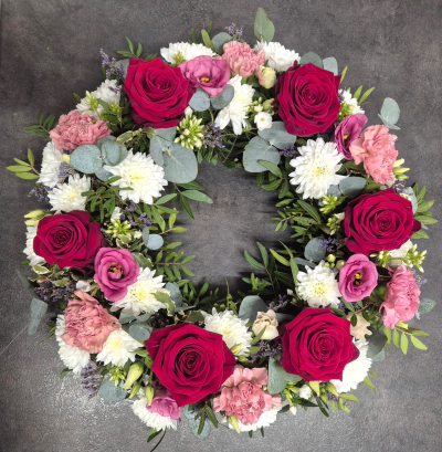 Mixed Loose Wreath - A beautifully handcrafted wreath featuring rich red, soft pink and white seasonal flowers, thoughtfully arranged as a heartfelt tribute to celebrate a cherished life.